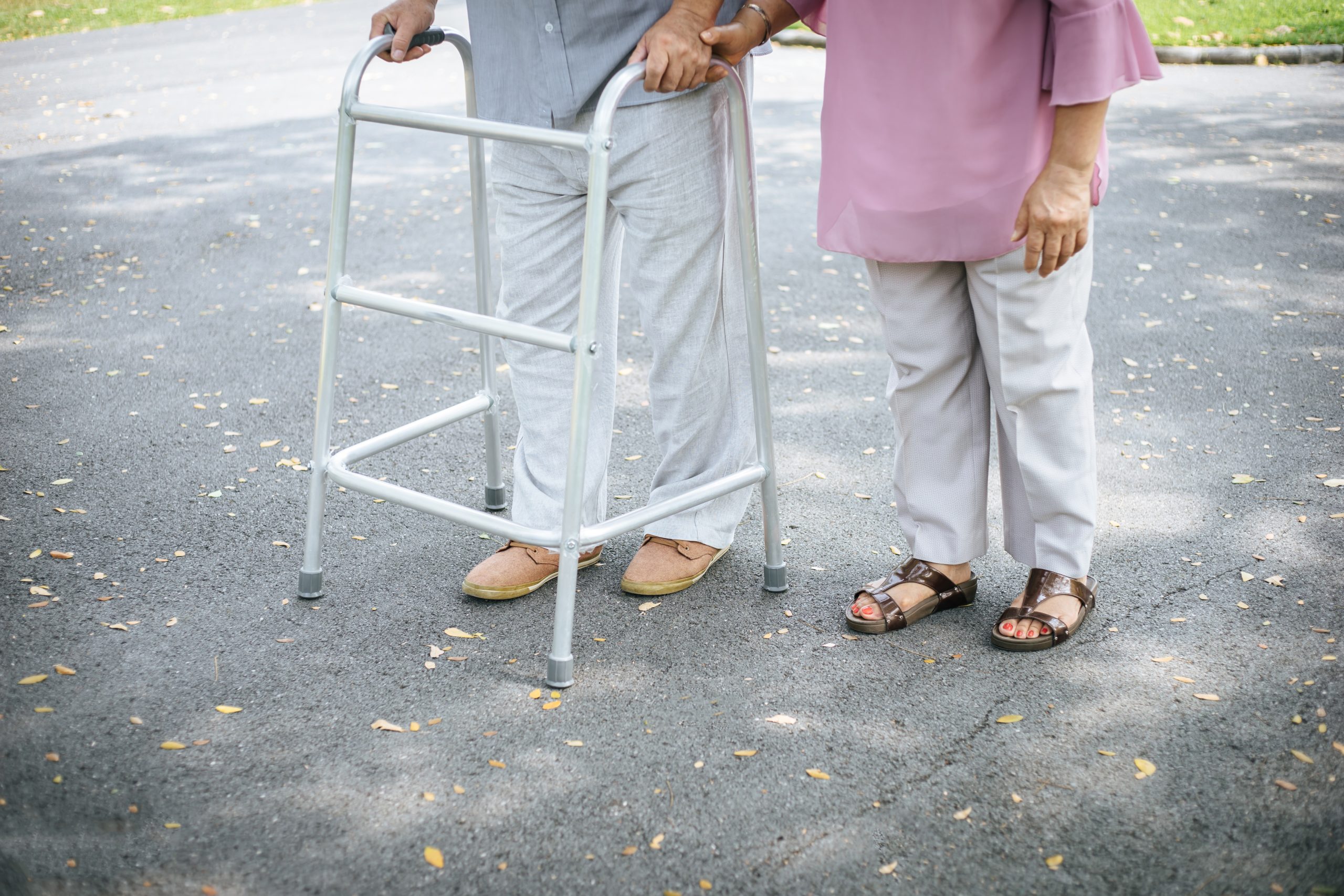 assisting her senior patient who's using a walker for support