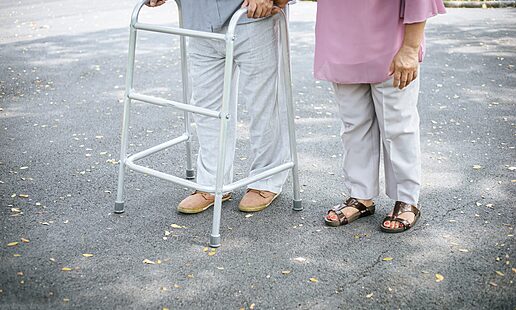 assisting her senior patient who's using a walker for support